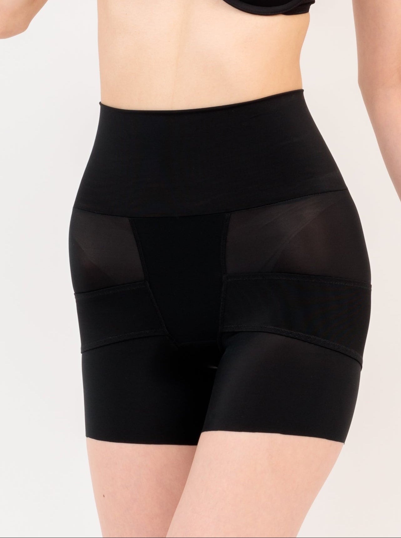Black shapewear shorts worn by a person on a plain background
